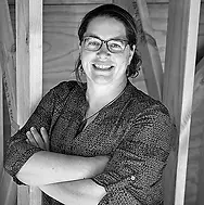 Black and white image of Kim smiling with her arms folded